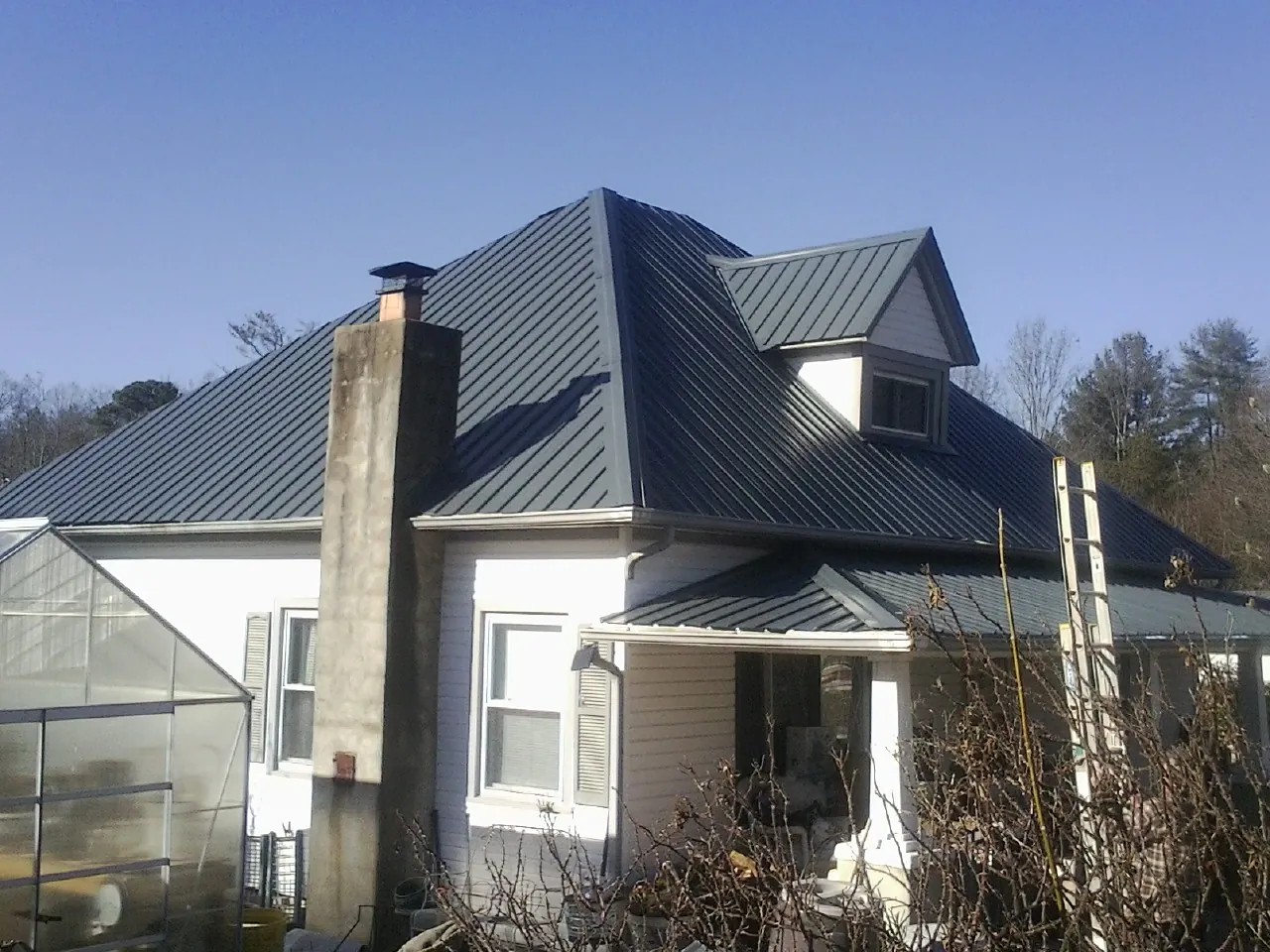 Dark blue standing seam metal roof on a white farmhouse with dormer — Slate & Tile Roof Repair by Roofing Brothers in Ellwood City