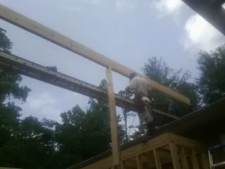 Carpenter setting a ridge beam over a new addition frame — Ice Dam Removal by Roofing Brothers in Ellwood City