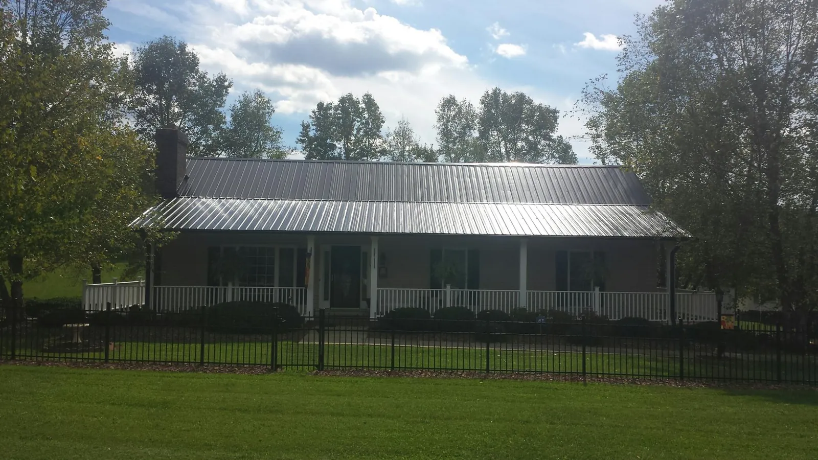 Gray metal roof on a brick ranch with a full width front porch — Gutter Guard Installation work by our crew in Ellwood City