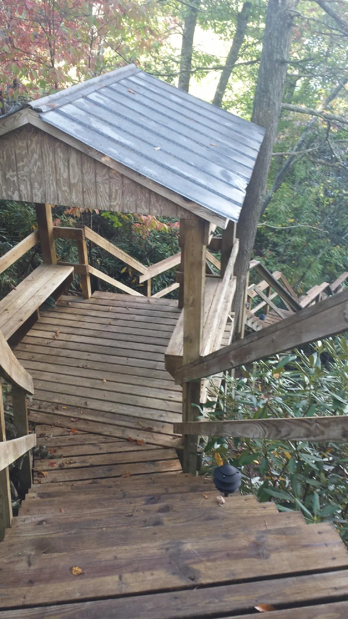 Metal roofed shelter over wooden steps on a wooded walkway — Skylight Repair & Installation work by our crew in Ellwood City