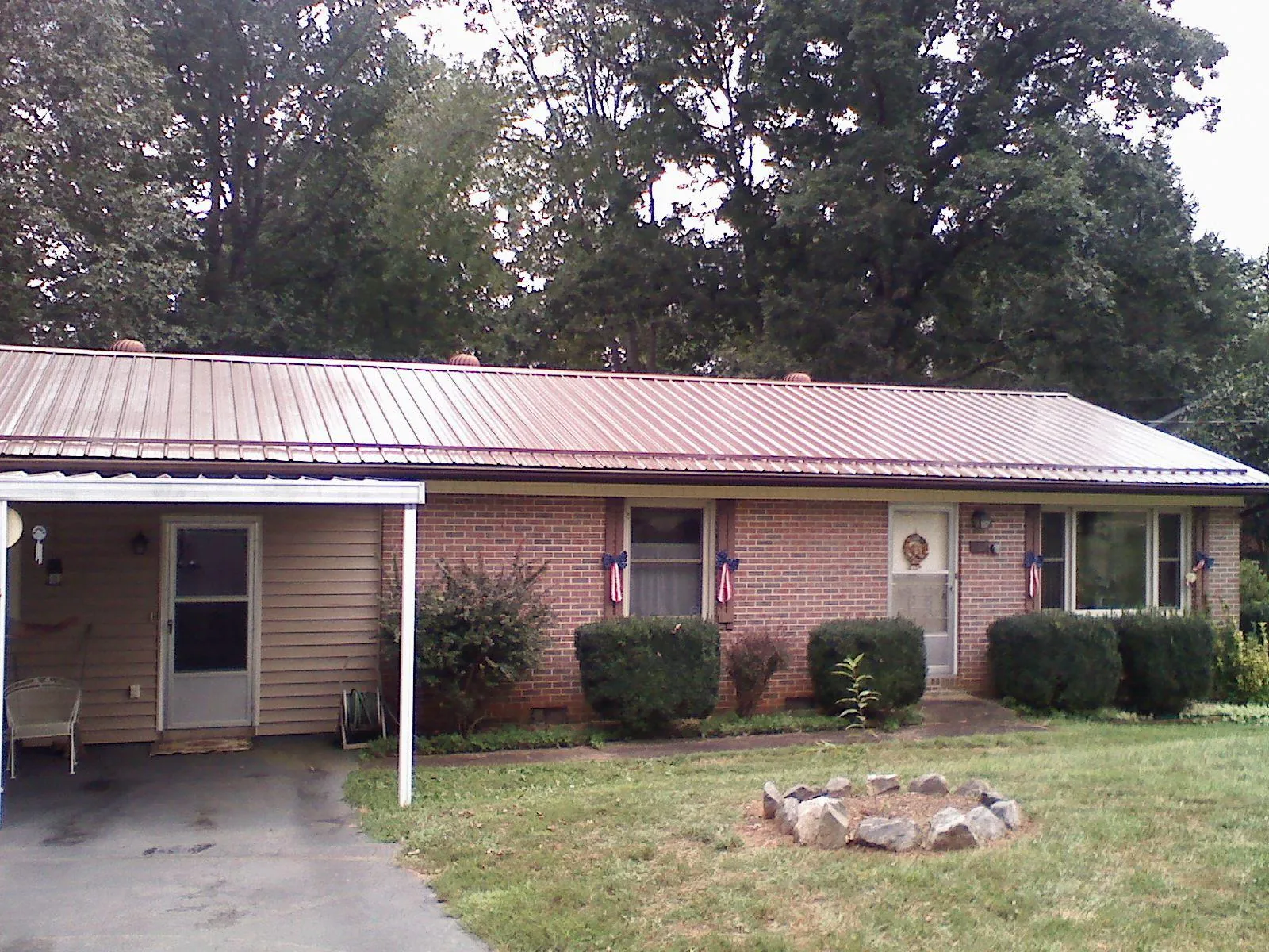 Bronze metal roof and carport on a brick ranch home — Roof Repair work by our crew in Ellwood City