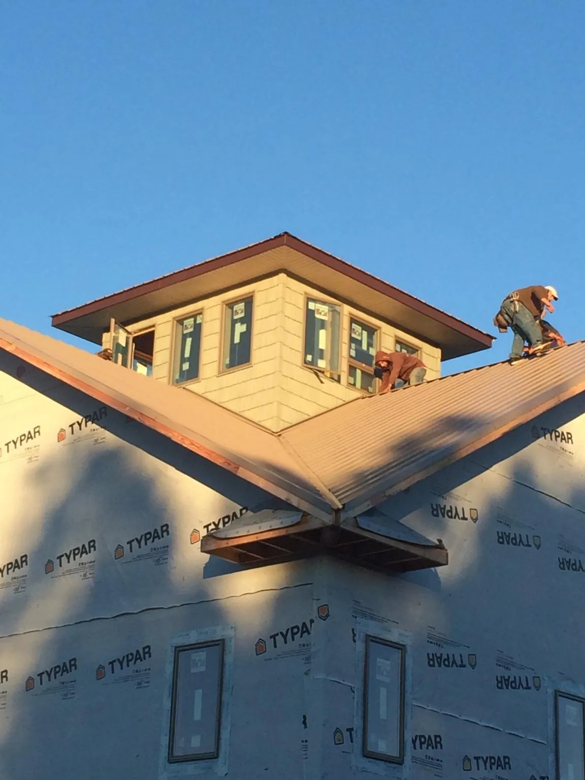 Roofers working around a rooftop cupola on a new metal roof at sunset — Roof Waterproofing in Ellwood City by Roofing Brothers